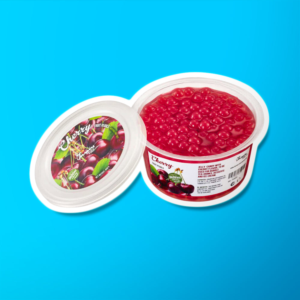 Une boite sur fond bleu remplie de perles rouges et à gauche le couvercle avec plusieurs cerises
