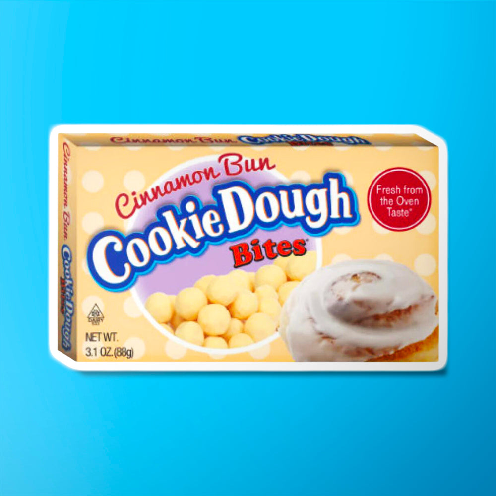 Un carton beige sur fond bleu avec des boules couleur crème et à droite un beignet couvert d’une glaçage blanc
