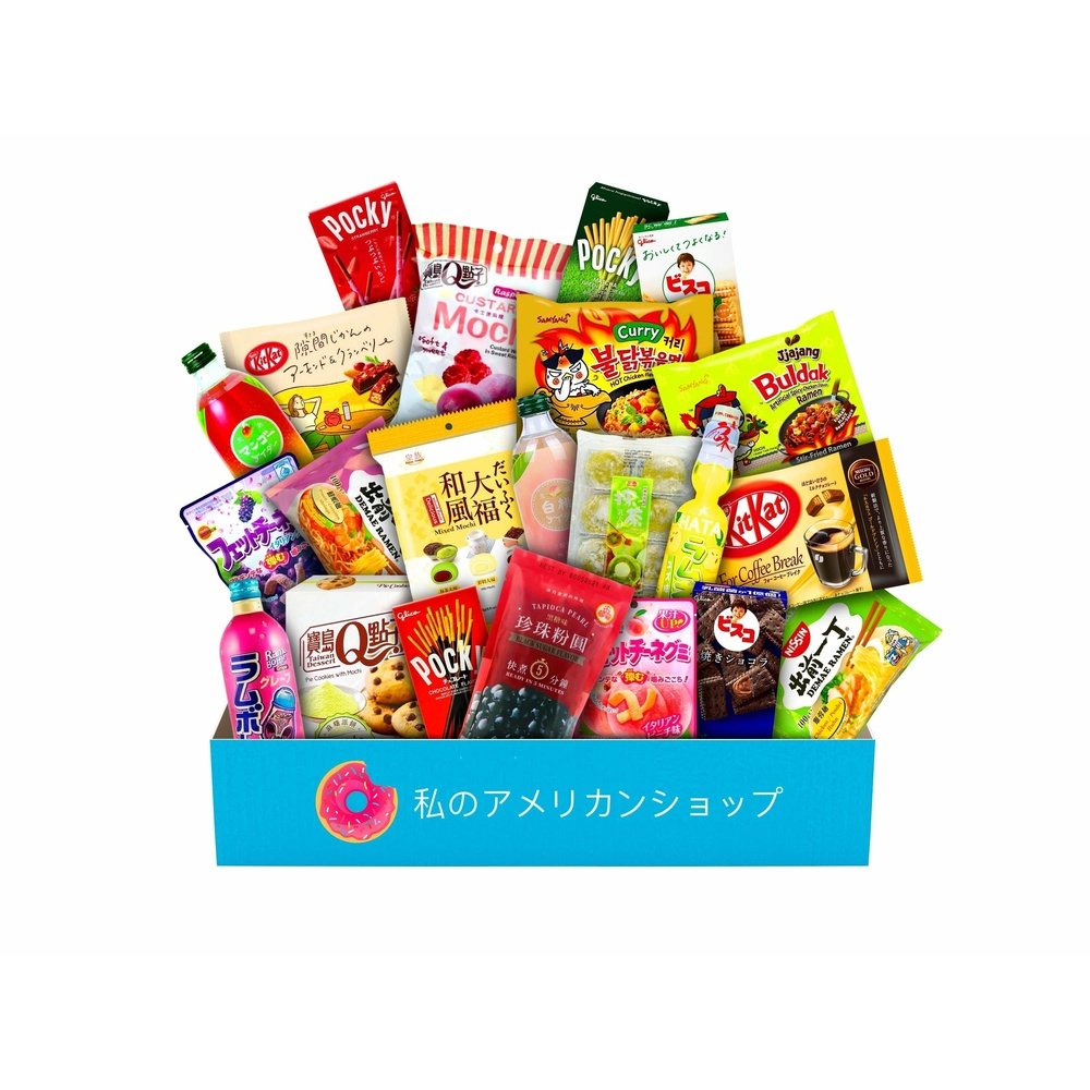 Un carton rectangulaire bleu contenant plein de snacks asiatiques comme des mochis roses, des biscuits en bâtonnet avec du chocolat noirs, des boules noirs de tapioca, une boisson jaune etc… Le tout sur fond blanc