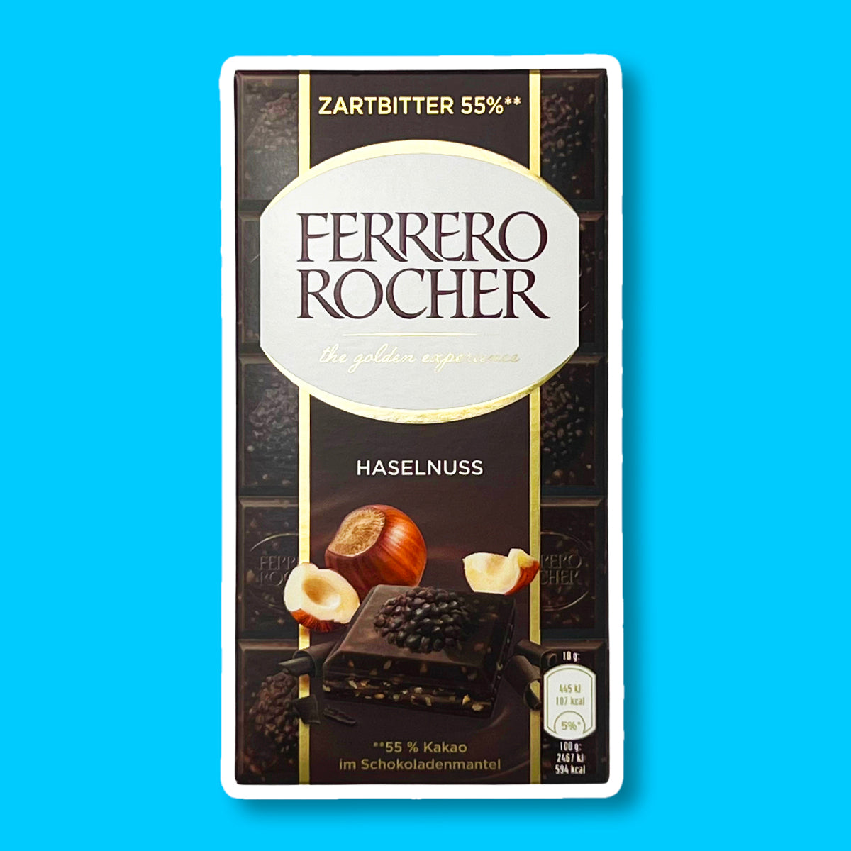 Un emballage de la couleur du chocolat noir avec un carré au chocolat noir et derrière une noisette entière et 2 éclats de part et d’autre. Le tout sur fond bleu