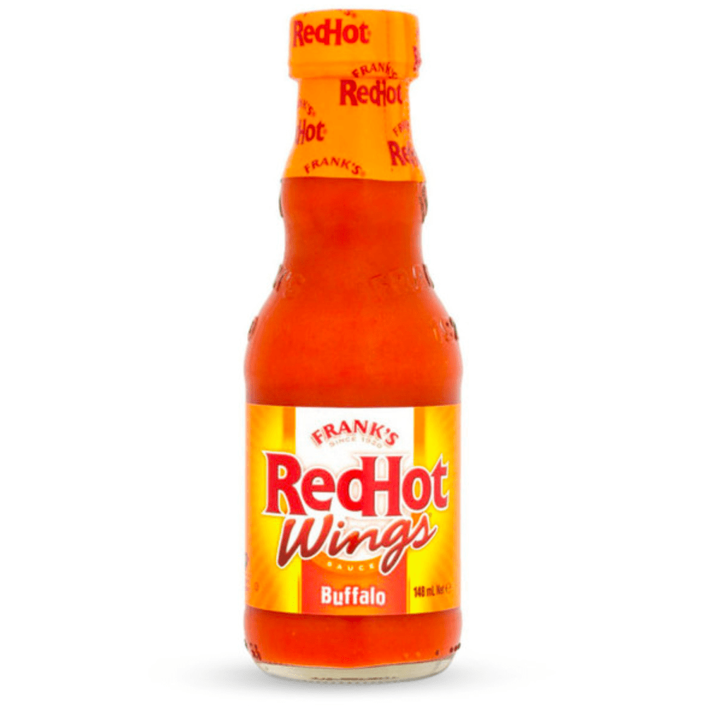 Une bouteille transparente avec une sauce rouge sur fond blanc et une étiquette rouge et jaune avec écrit « RedHot Wings » en grand