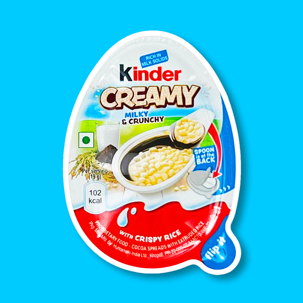 Un paquet blanc et orange sur fond bleu avec au centre un Kinder Creamy ouvert, on y voit le riz soufflé dans sa crème
