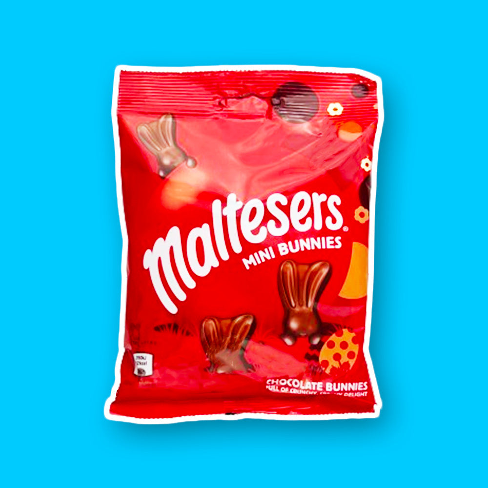 Un emballage rouge sur fond bleu avec des oreilles de lapin en chocolat qui sortent du sol