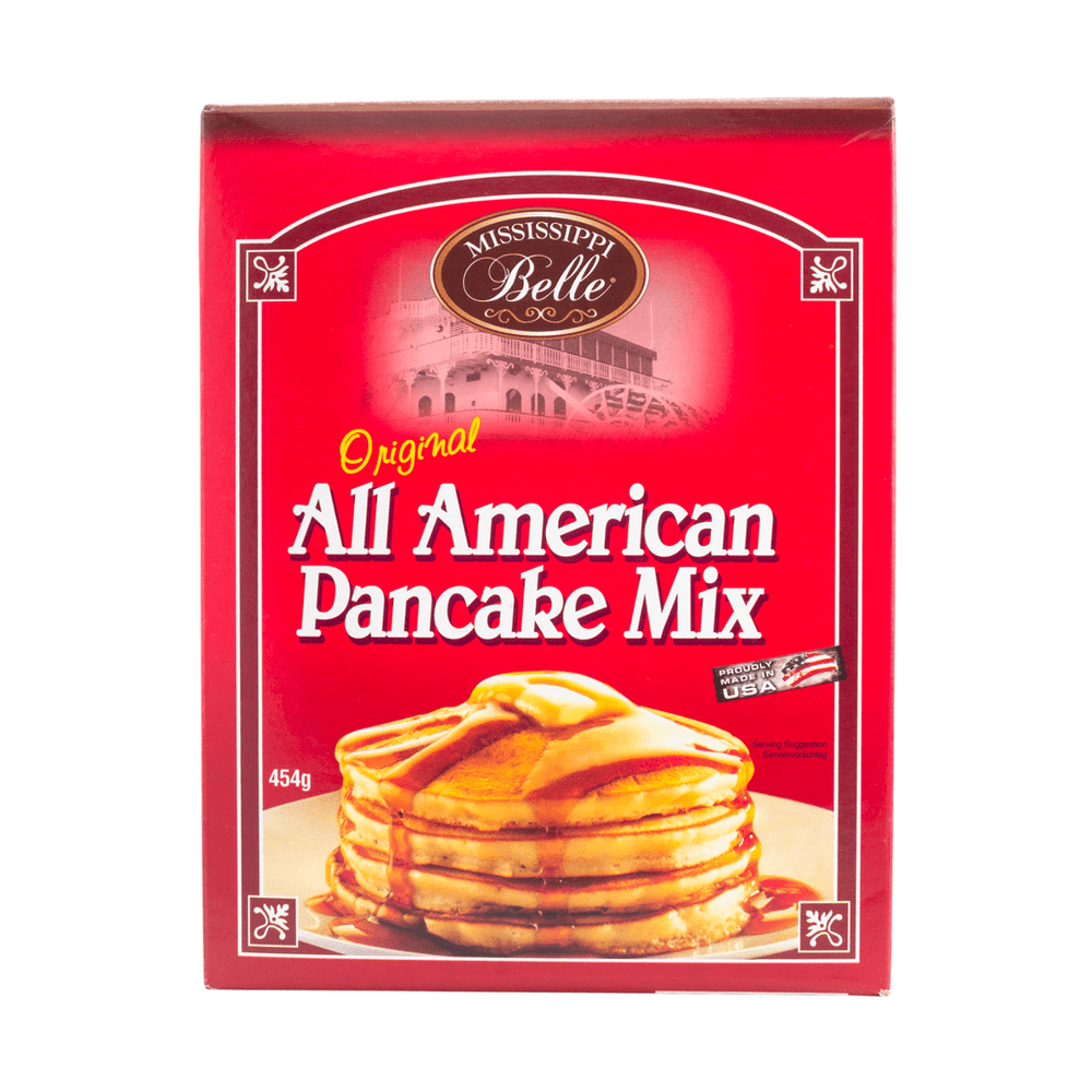 Un carton rouge sur fond blanc avec des pancakes empilés les uns sur les autres, au-dessus du sirop d’érable et un carré de beurre dans une assiette blanche