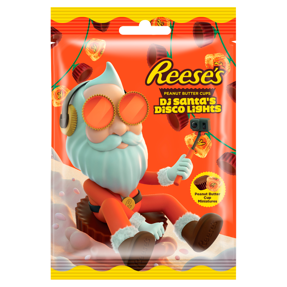 Un emballage orange avec un père Noël stylé qui se filme entrain de descendre une montage enneigée assis sur un chocolat Reese’s géant le tout sur un fond blanc