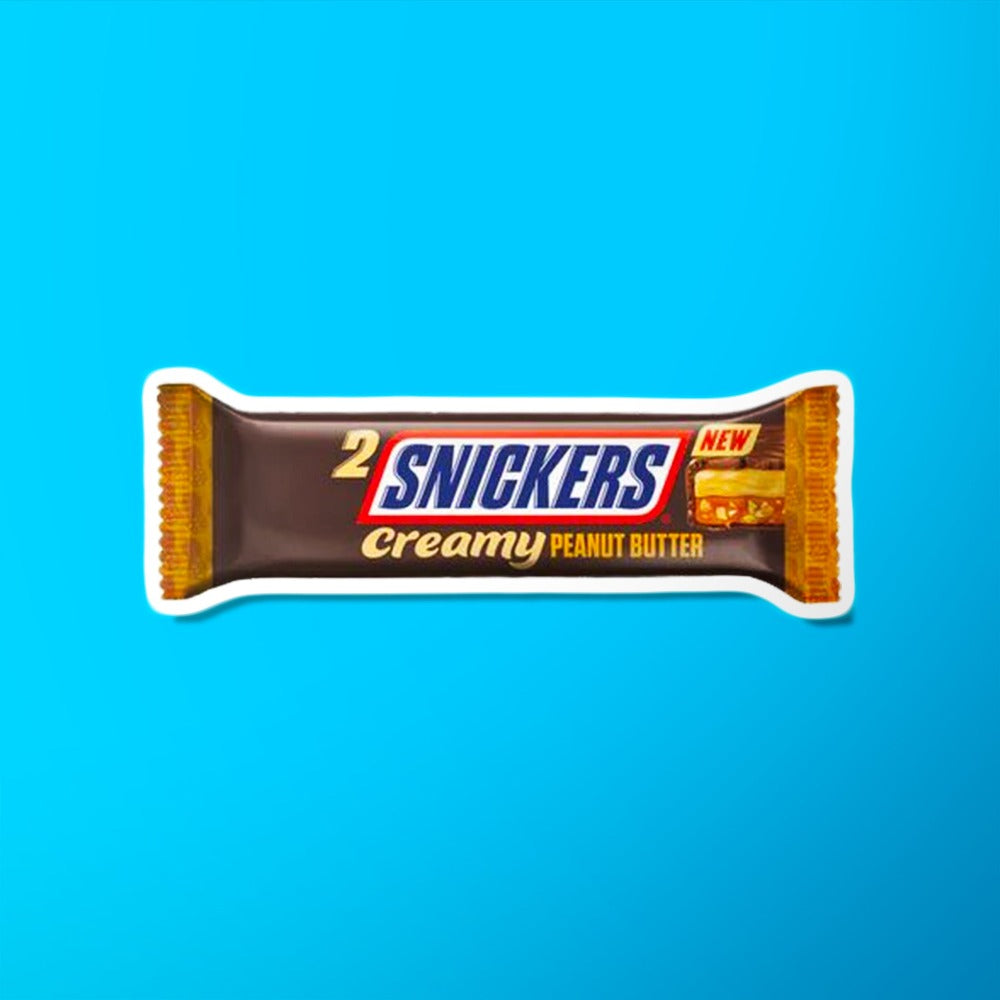 Un emballage marron sur fond bleu avec au centre écrit « Snickers » en bleu et sur le côté droit il y a une barre chocolatée coupée, on y voit du caramel et du biscuit