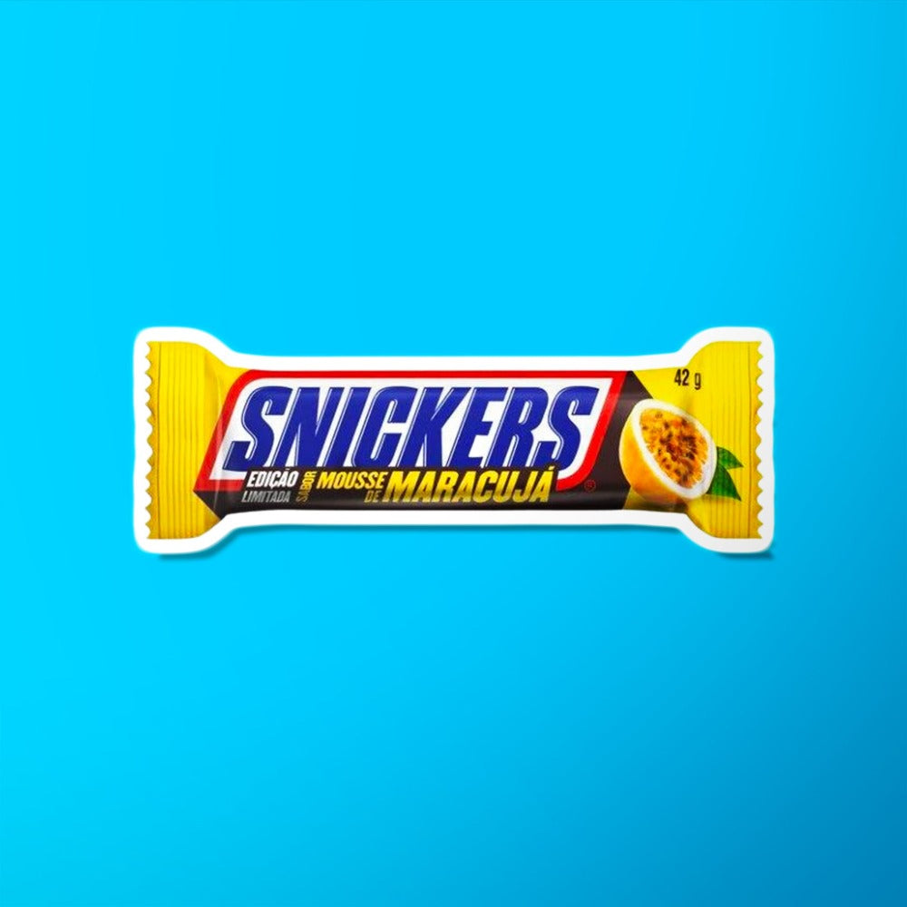 Un emballage jaune sur fond bleu avec au centre écrit « Snickers » en bleu et sur le côté droit il y a un demi maracuja