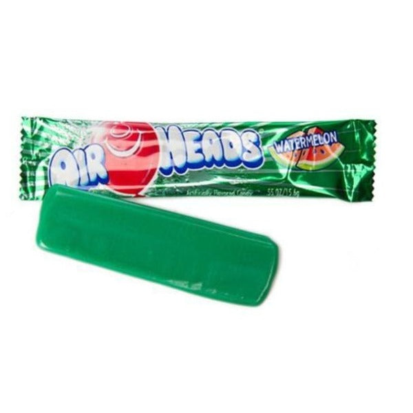 Un paquet individuel vert sur fond blanc avec un ballon rouge qui sourit. Sur le côté droit, il y a 2 morceaux de pastèque et devant il y un bonbon déballé de couleur verte