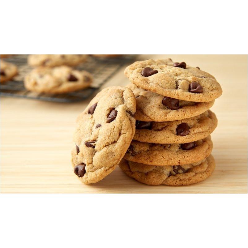 6 cookies aux pépites de chocolat sur une table en bois et à l'arrière des cookies sur une grille de four