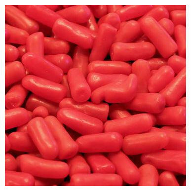 Plusieurs bonbons rouges en formes de capsules, entassés les uns sur les autres