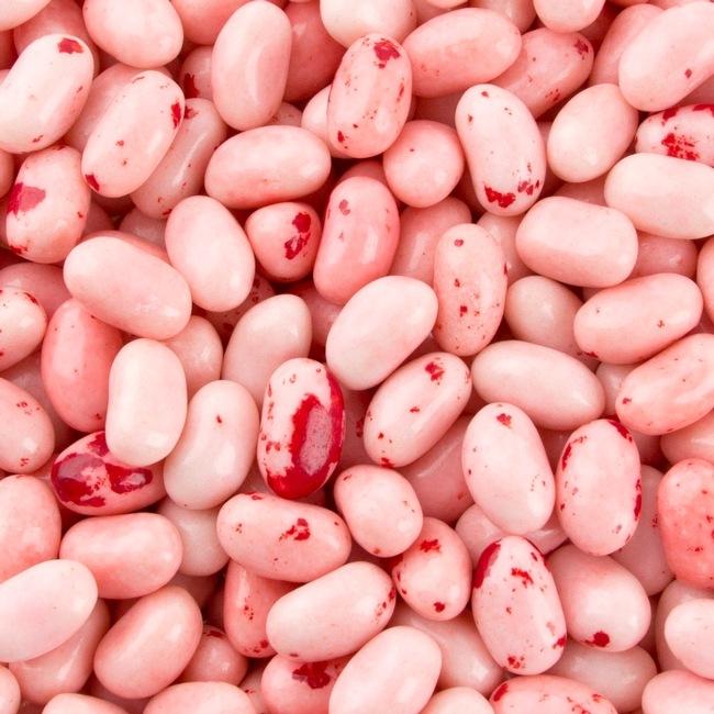 Un tas de bonbons en forme de haricots roses avec des petites tâches rouges