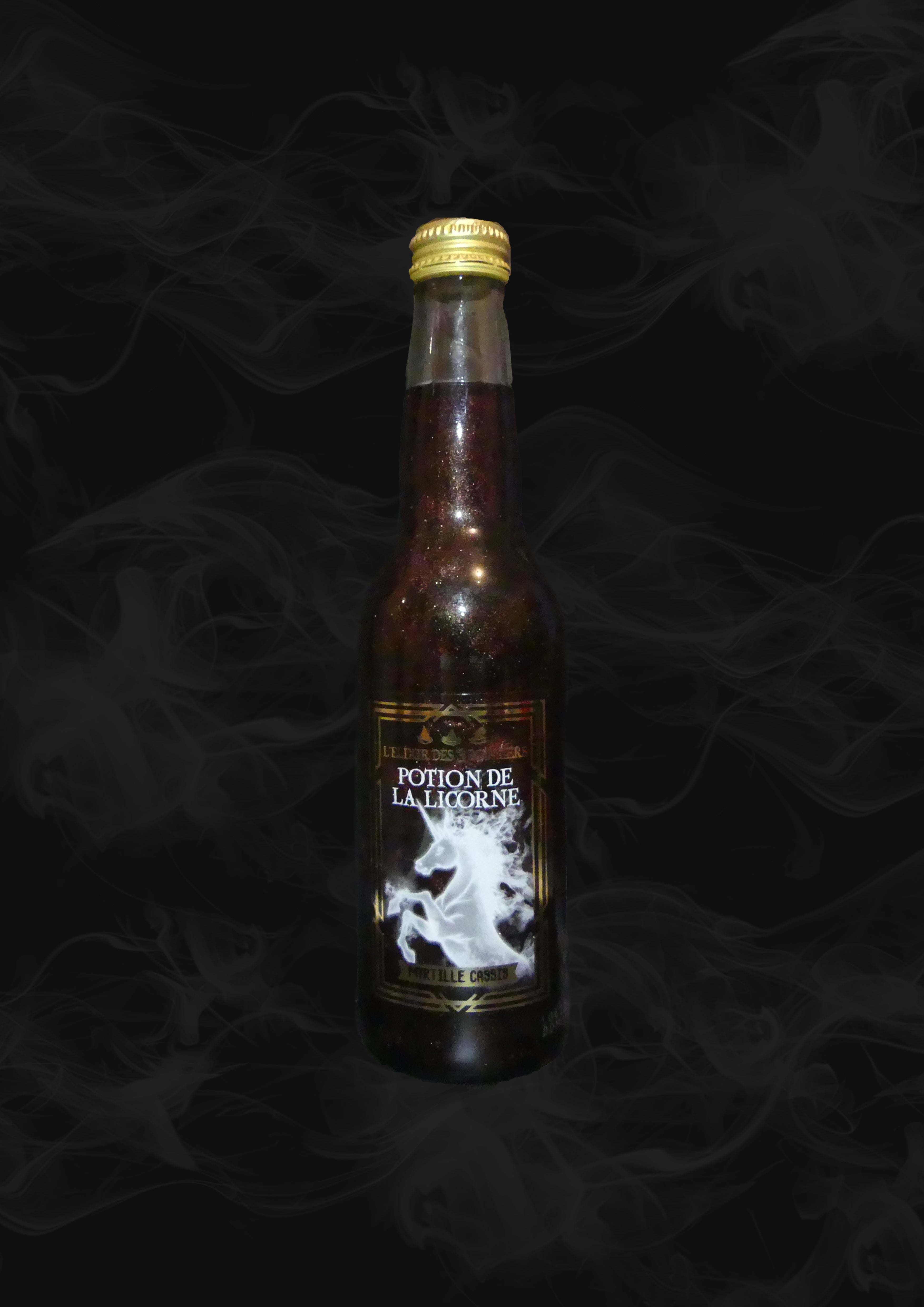 Une bouteille transparente avec une boisson pailletée noire et sur l’étiquette une licorne blanche. Le tout sur fond noir avec de la fumée