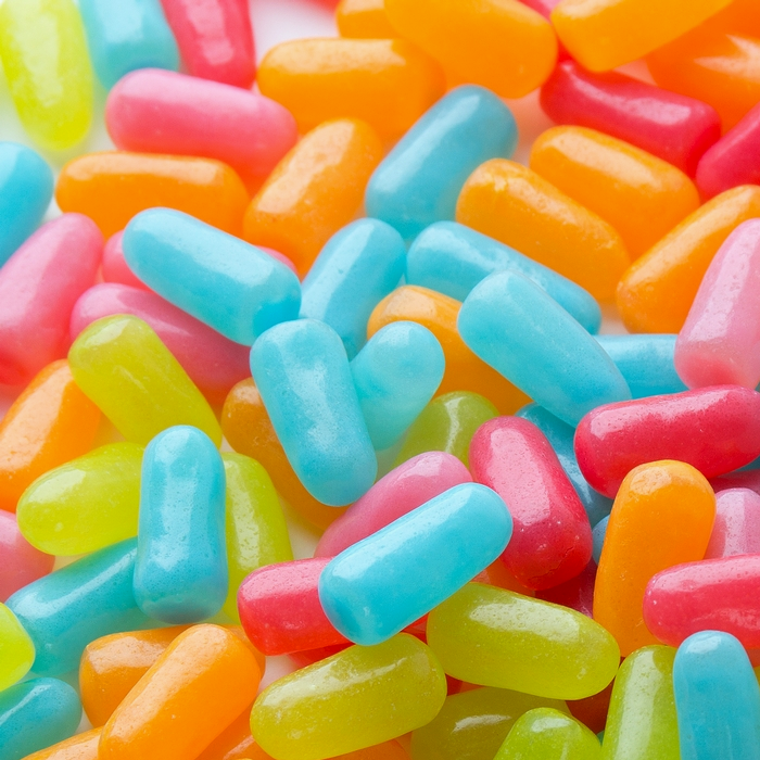 Des bonbons en formes de pilules jaune, bleu, orange et rose