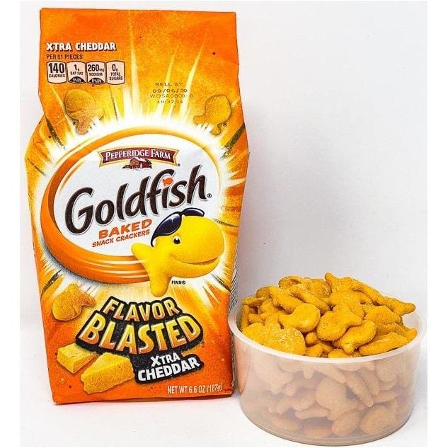 A gauche un paquet orange avec au centre un petit poisson jaune à lunettes de soleil et à droite un bol transparent rempli de biscuits oranges en forme de poisson
