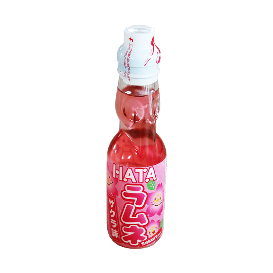 Une bouteille transparente sur fond blanc avec une boisson légèrement rosée, il y a une étiquette rose sur la moitié basse de la bouteille. Il y a des fleurs de cerisiers qui sourient